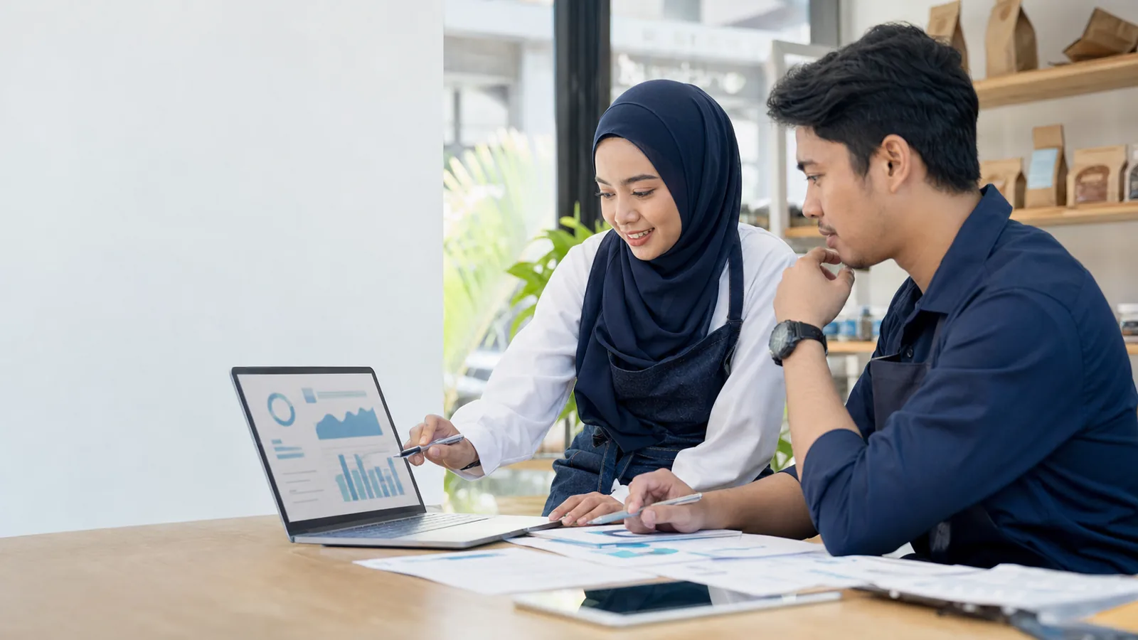 Malaysian SME owners reviewing website and search growth plans on a laptop