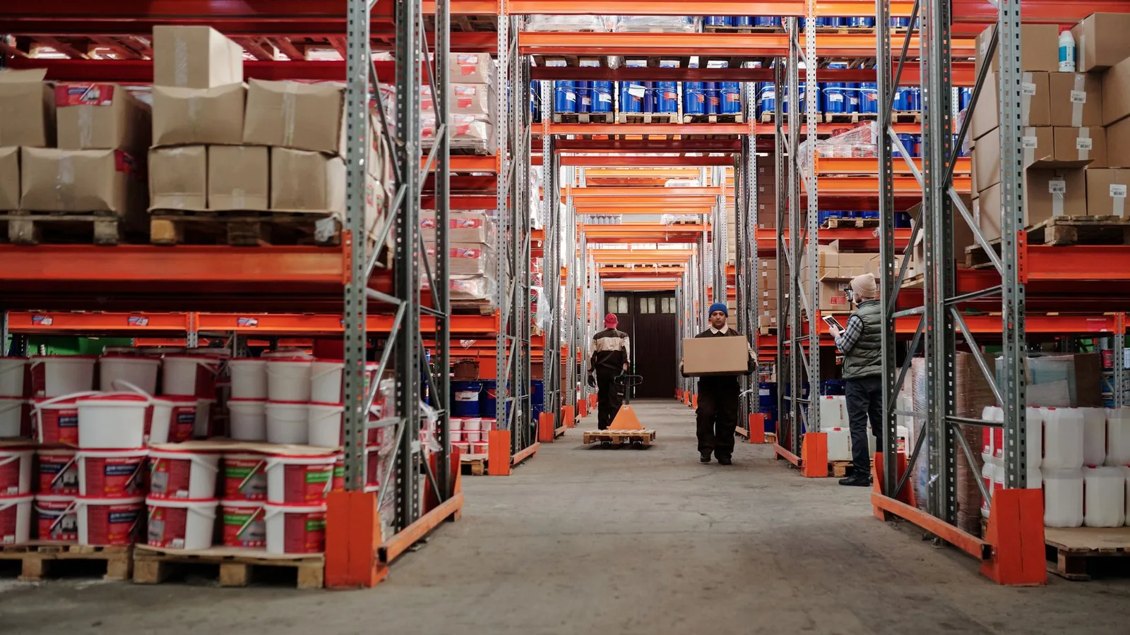 Workers handling inventory in a large industrial warehouse